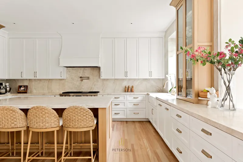 Bright white kitchen with a light-wood island and woven stools