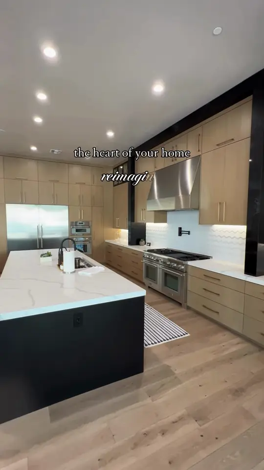 Modern kitchen: light wood walls, black island, waterfall quartz