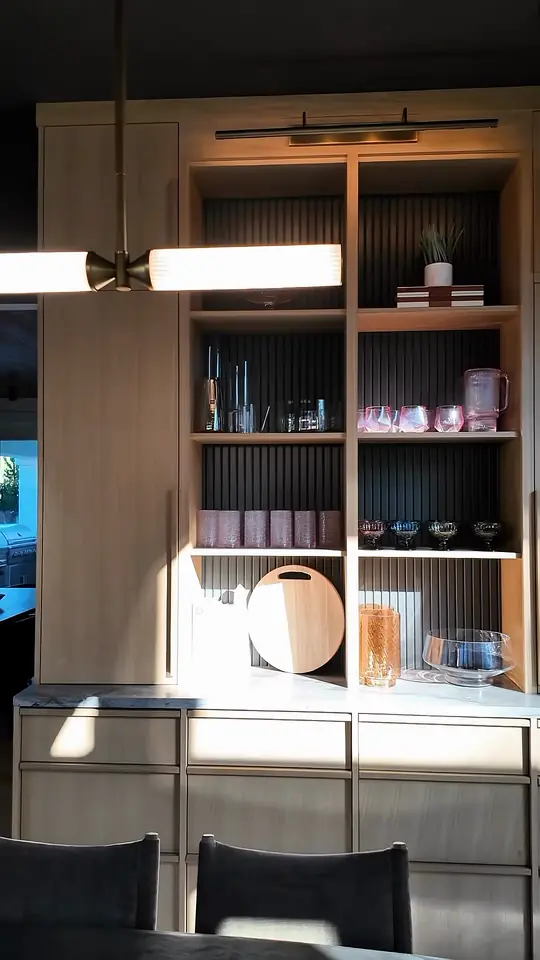 Light-wood dining hutch with a fluted dark back and lit shelves