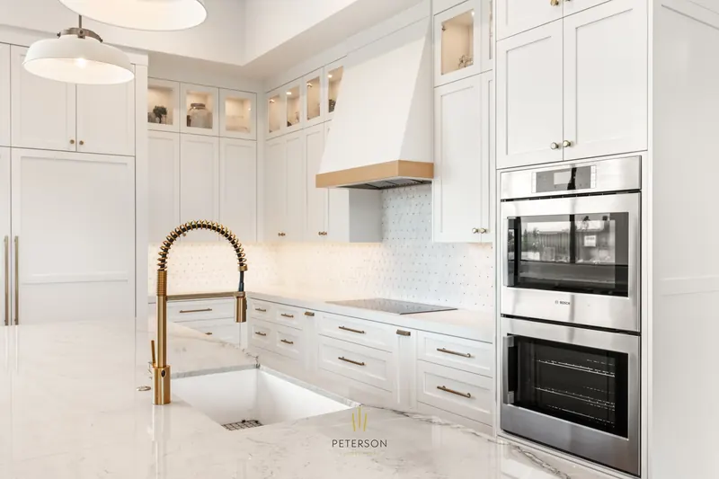 White kitchen with a plaster hood and brass faucet