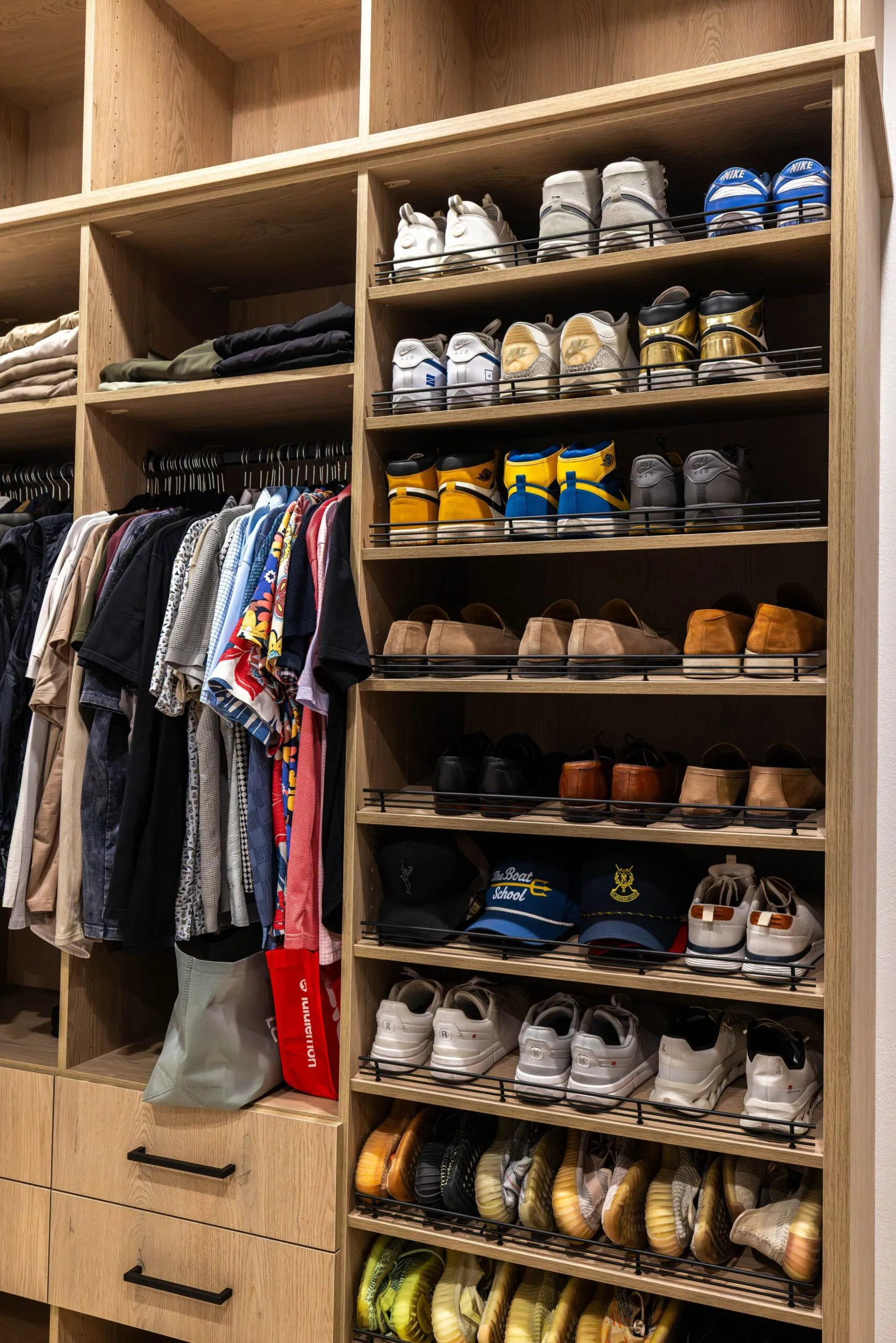 Floor-to-ceiling shoe wall beside double hanging in a custom closet