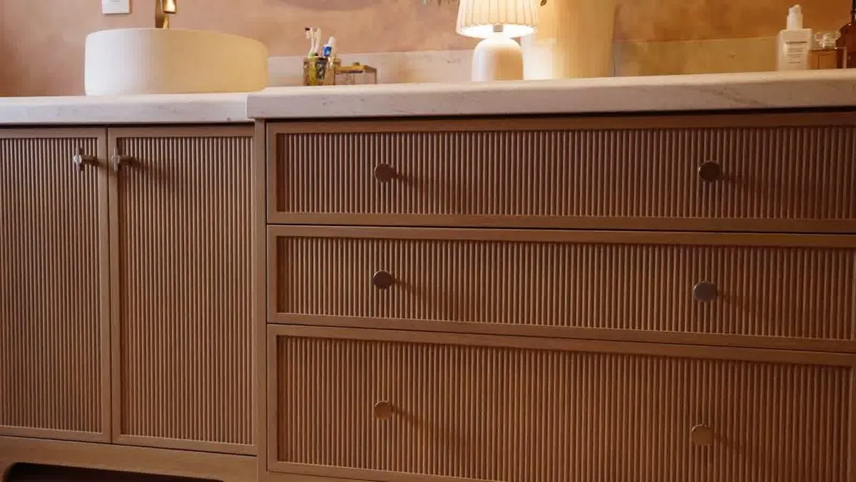 Fluted wood cabinet drawer fronts with custom hardware in a remodeled bungalow kitchen