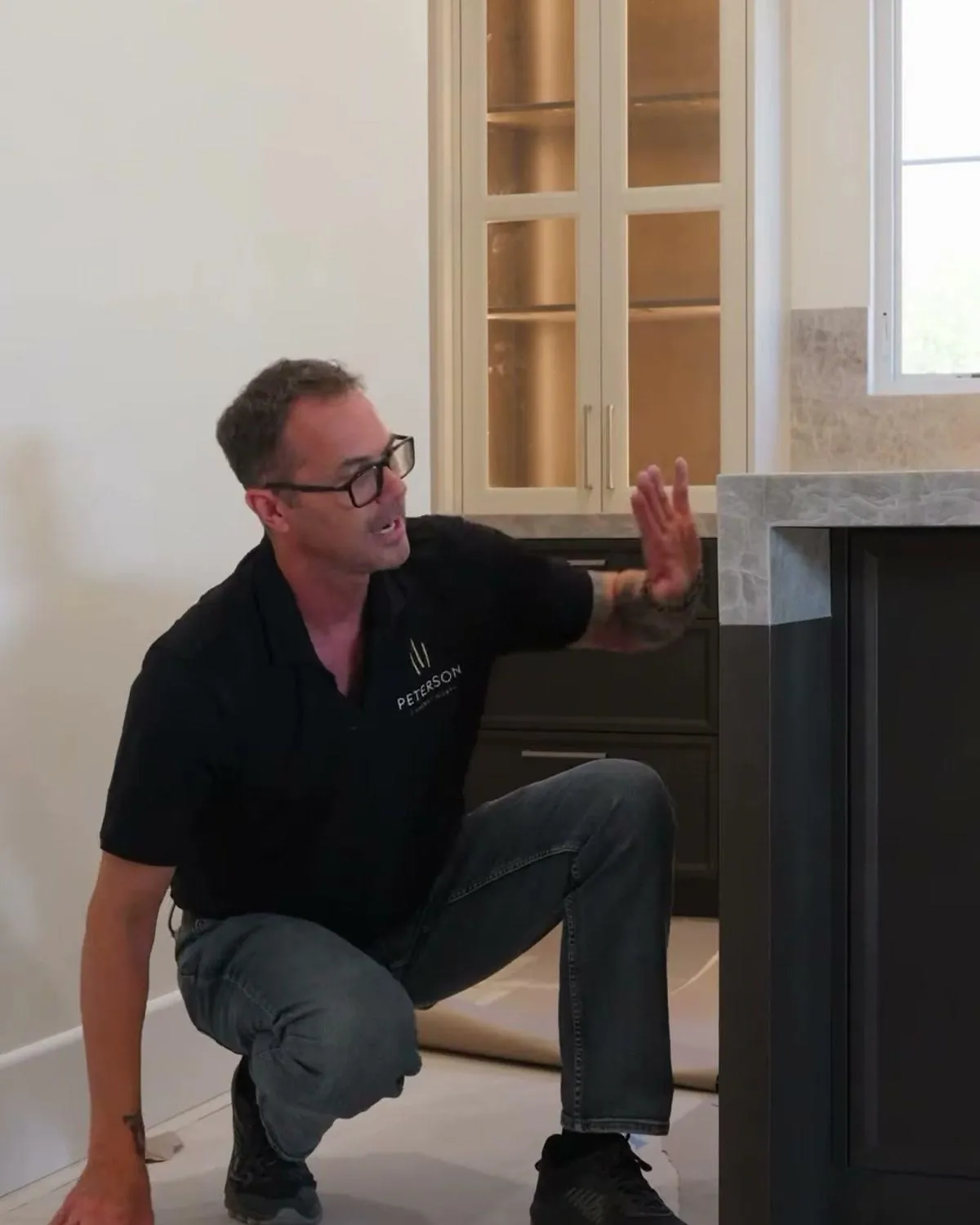 Cabinet maker pointing at a dark island end panel on an unfinished kitchen floor