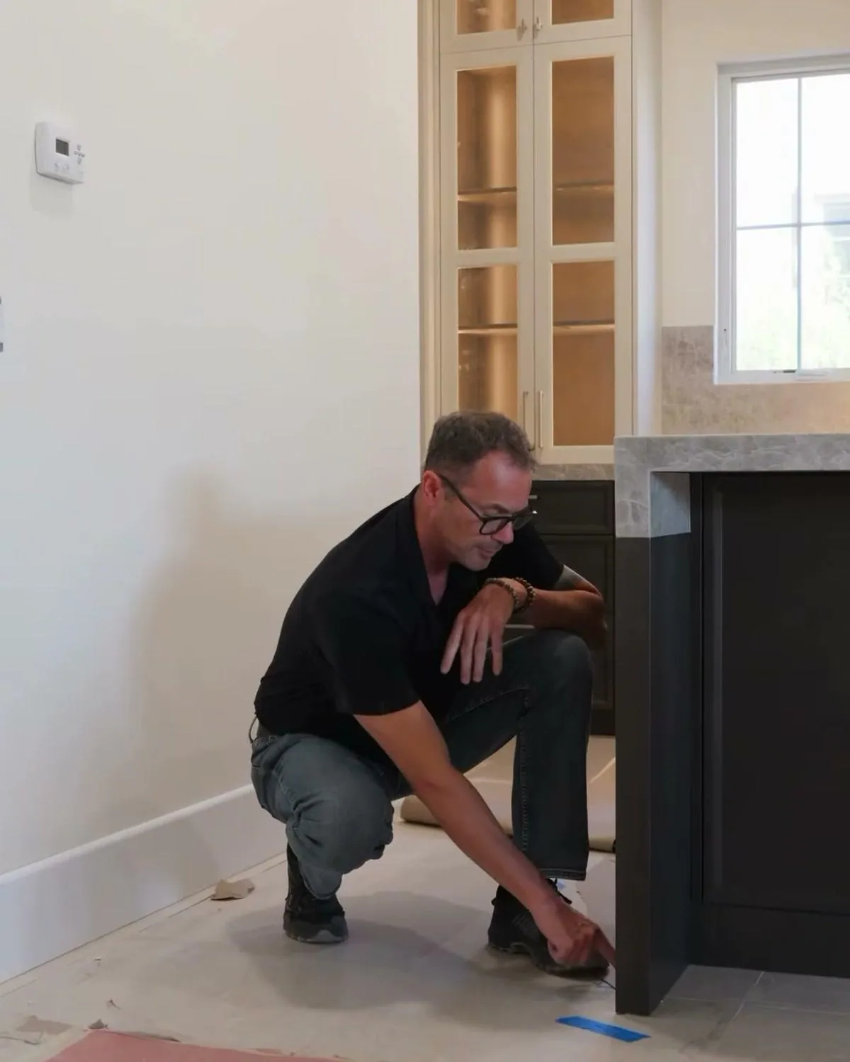 Dave Peterson pointing to the floor line beside a custom cabinet island in Las Vegas