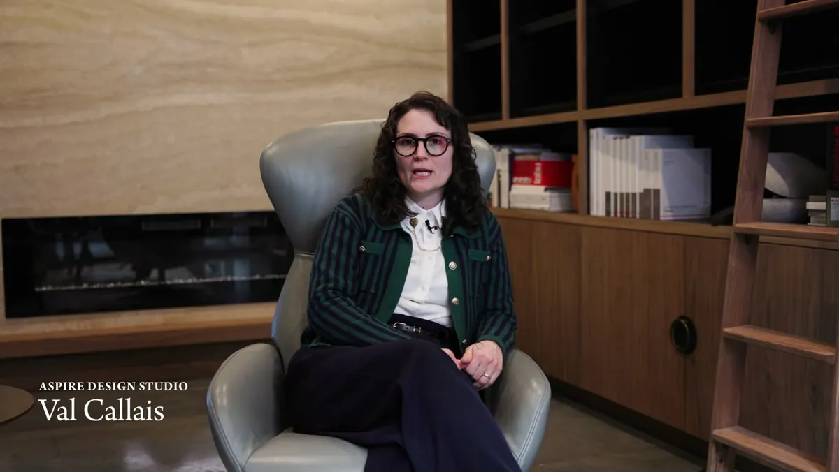 Interior designer Val Callais seated in front of the custom white oak materials library at Aspire Design Studio
