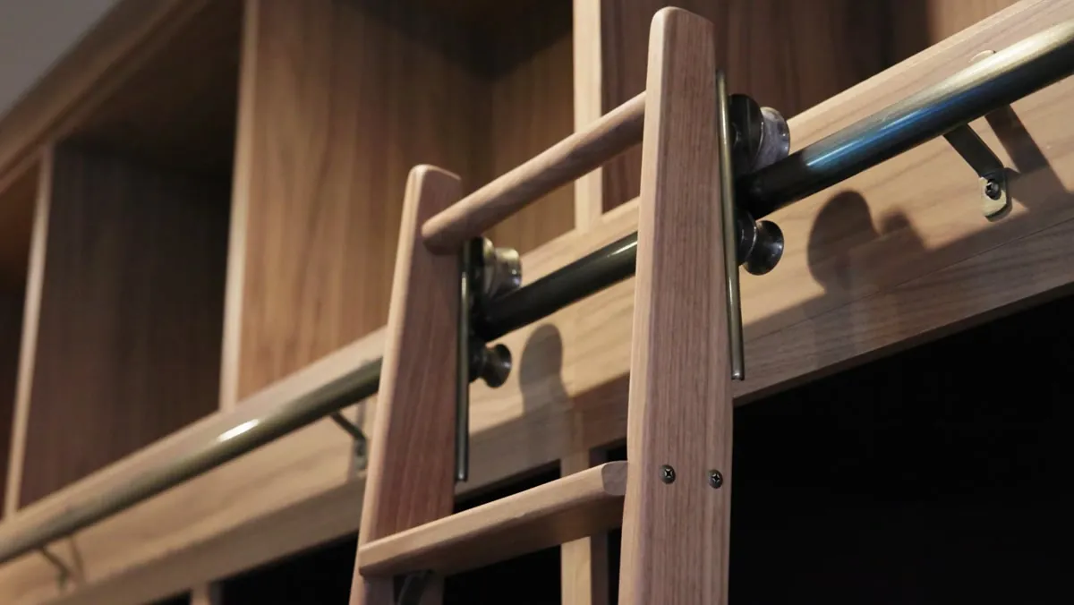 Custom rolling library ladder with antique brass fittings on white oak cabinetry