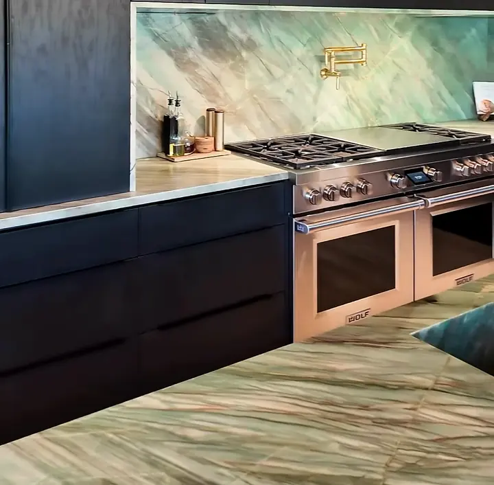 Green stone island with brass faucets and dark cabinetry